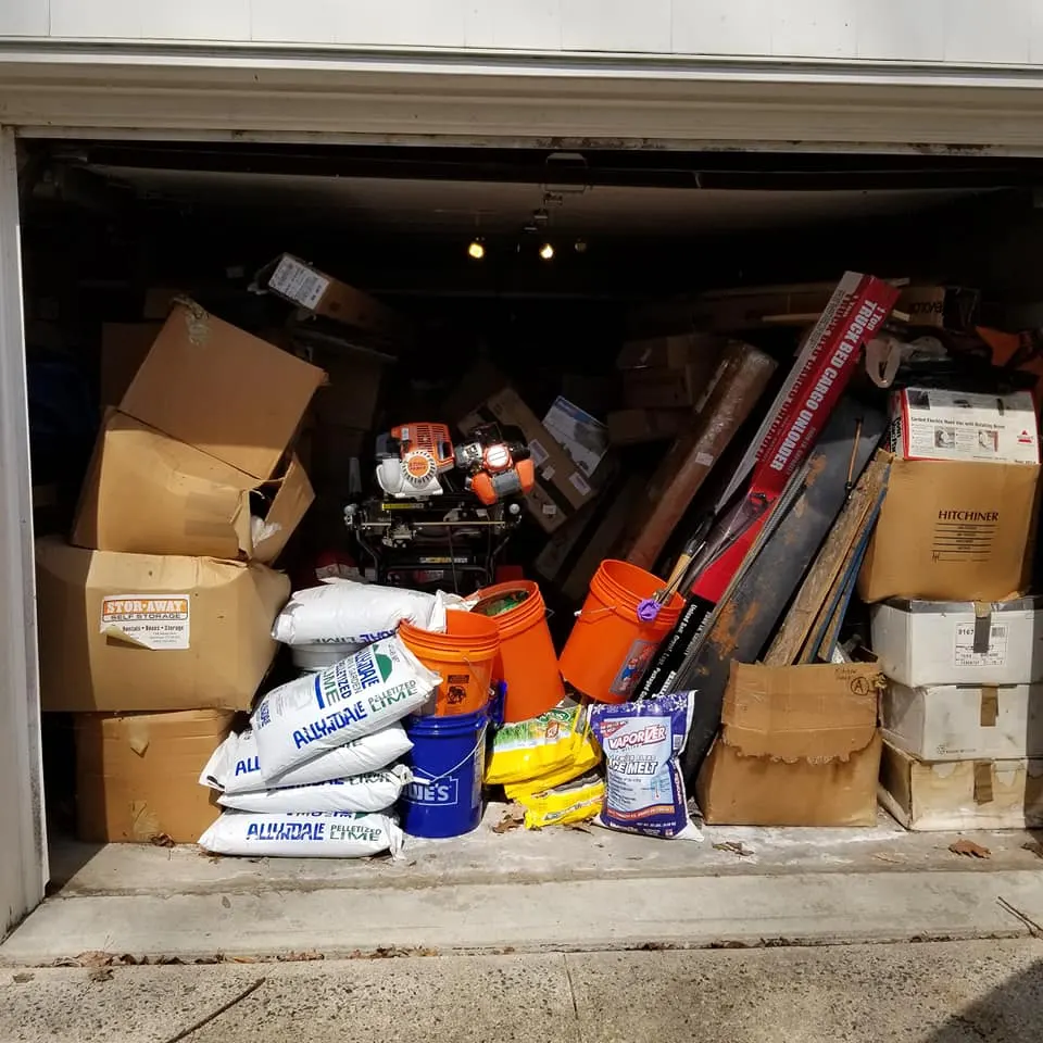 Garage packed floor to ceiling with boxes, buckets and tools before a cleanout